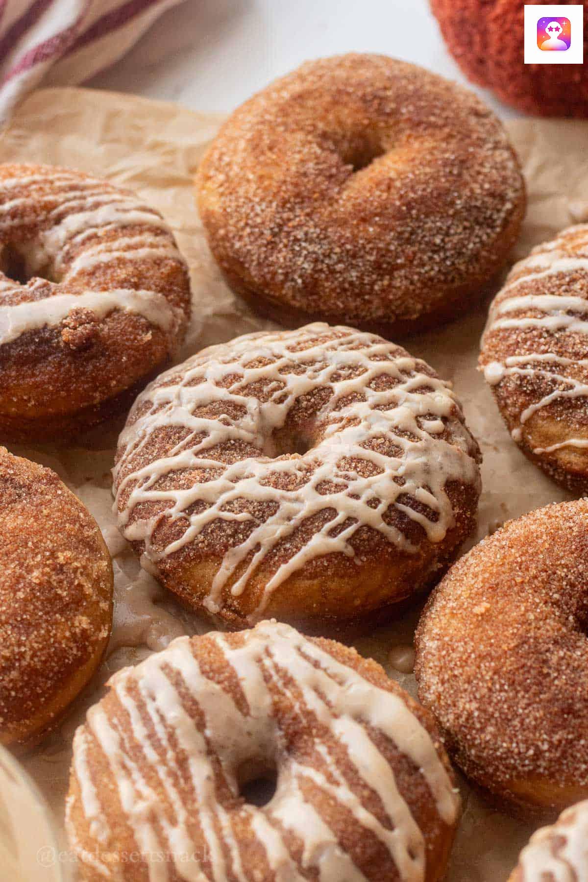 Baked glazed apple cider donuts on parchment paper.